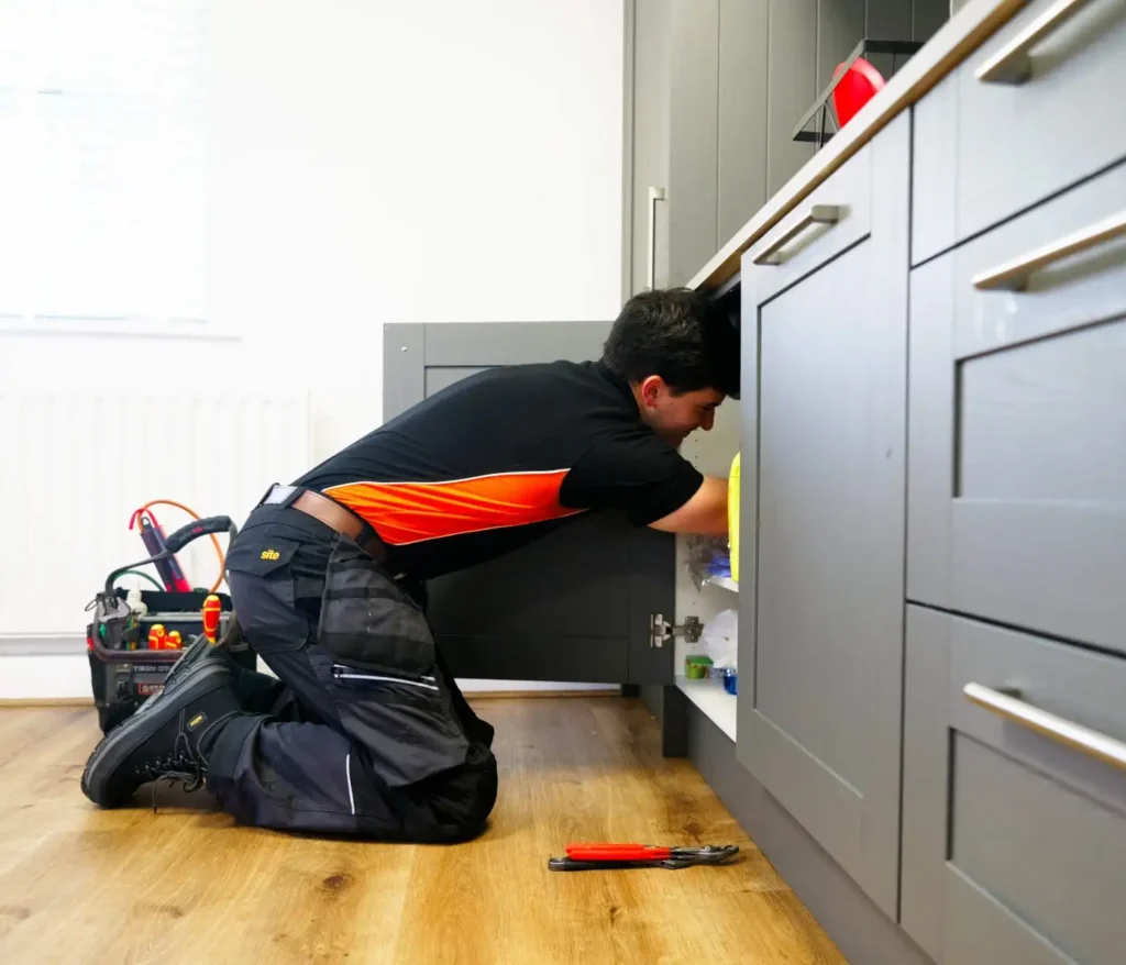 Plumber Fixing Leak In Kitchen LS1 Plumbing